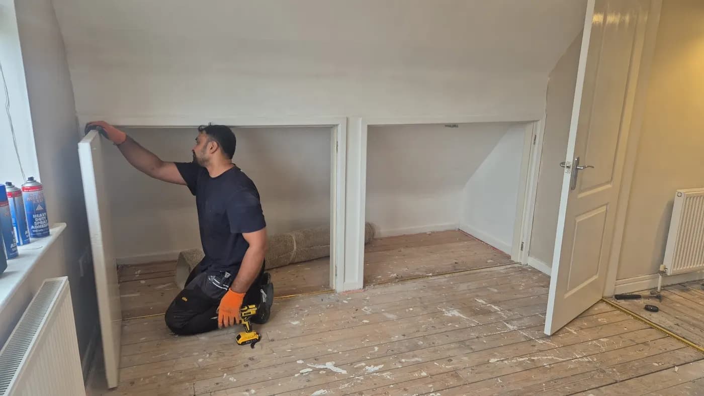 AF Fitted Wardrobes fitter installing a wardrobe door in a bedroom with sloping eaves
