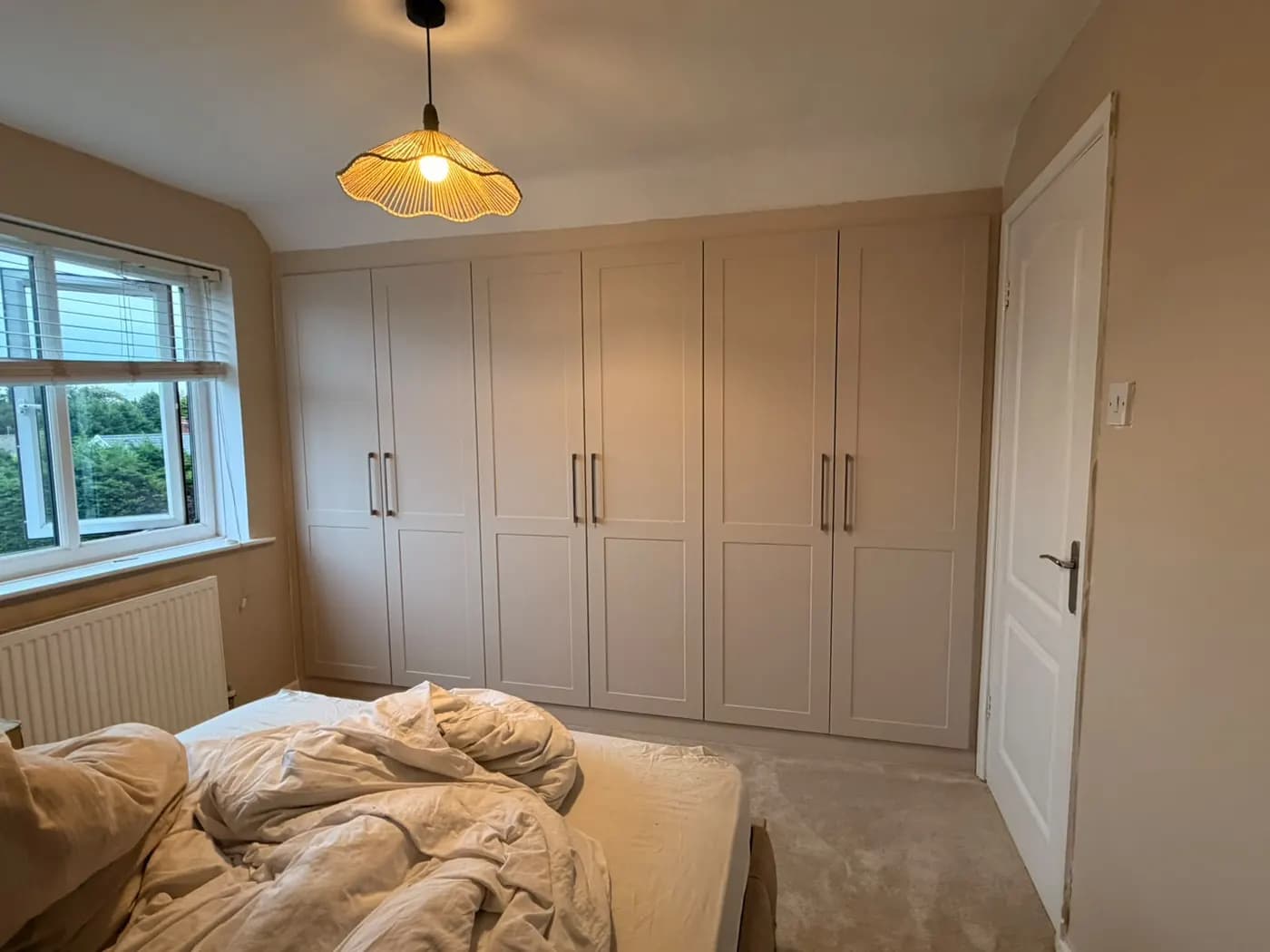 After: six-door cream shaker fitted wardrobe following the sloping ceiling in a bedroom