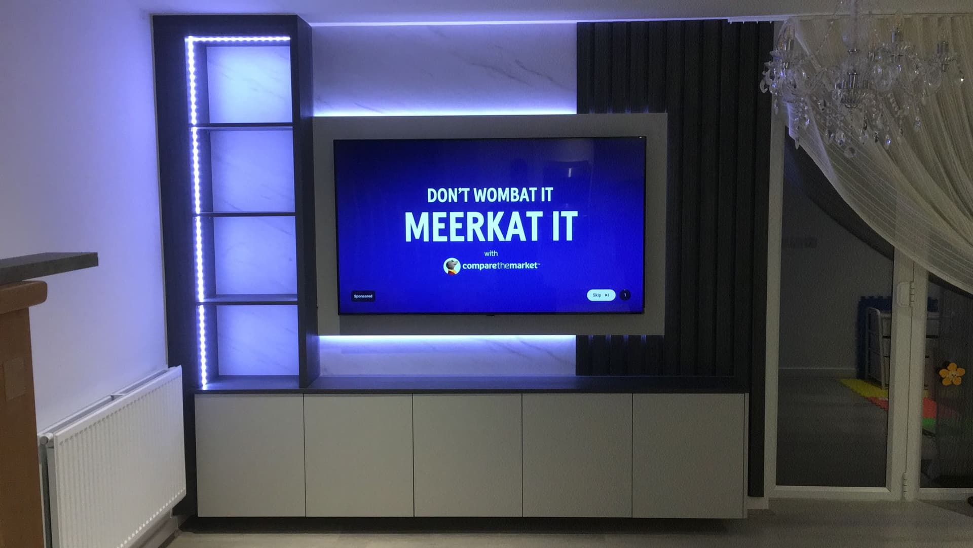 Custom media wall unit with integrated shelving and ambient lighting in a modern living room.