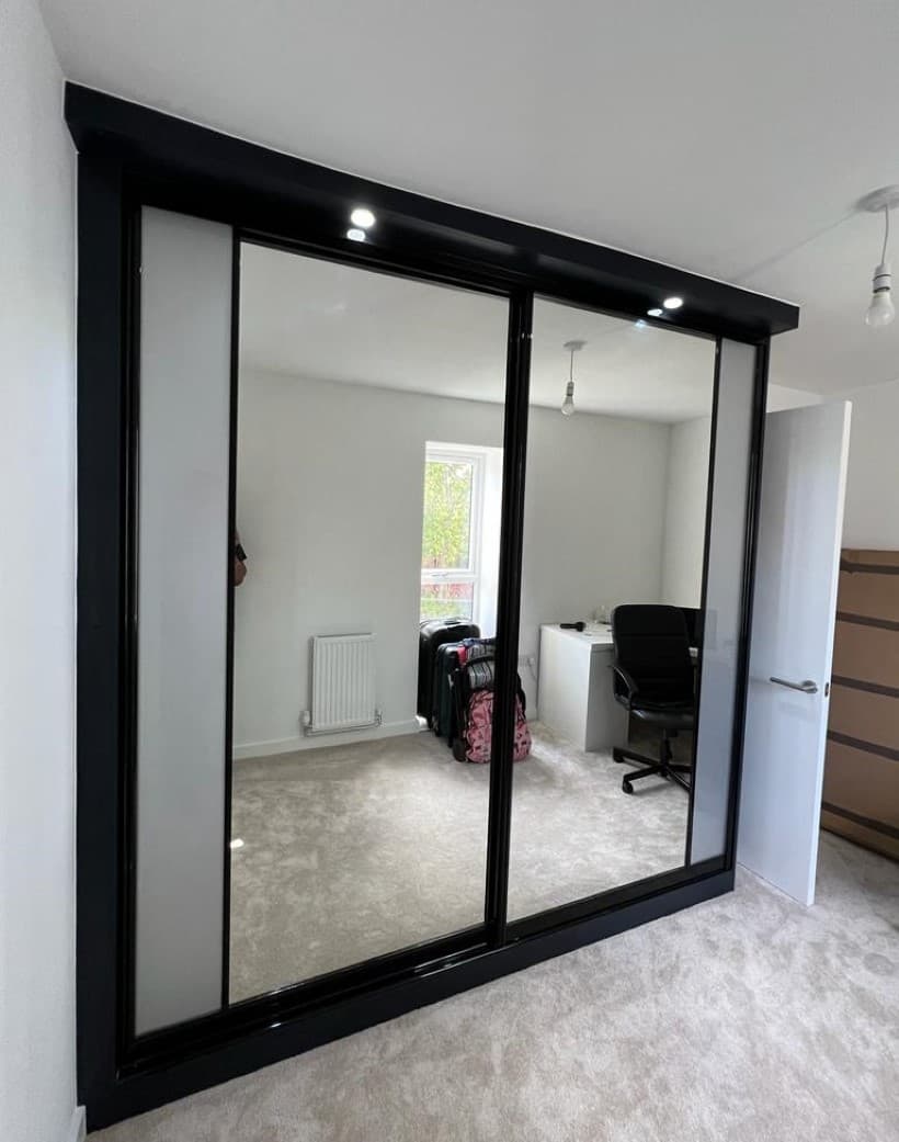 Mirrored sliding door wardrobe with slim gold framing, fitted in Manchester.