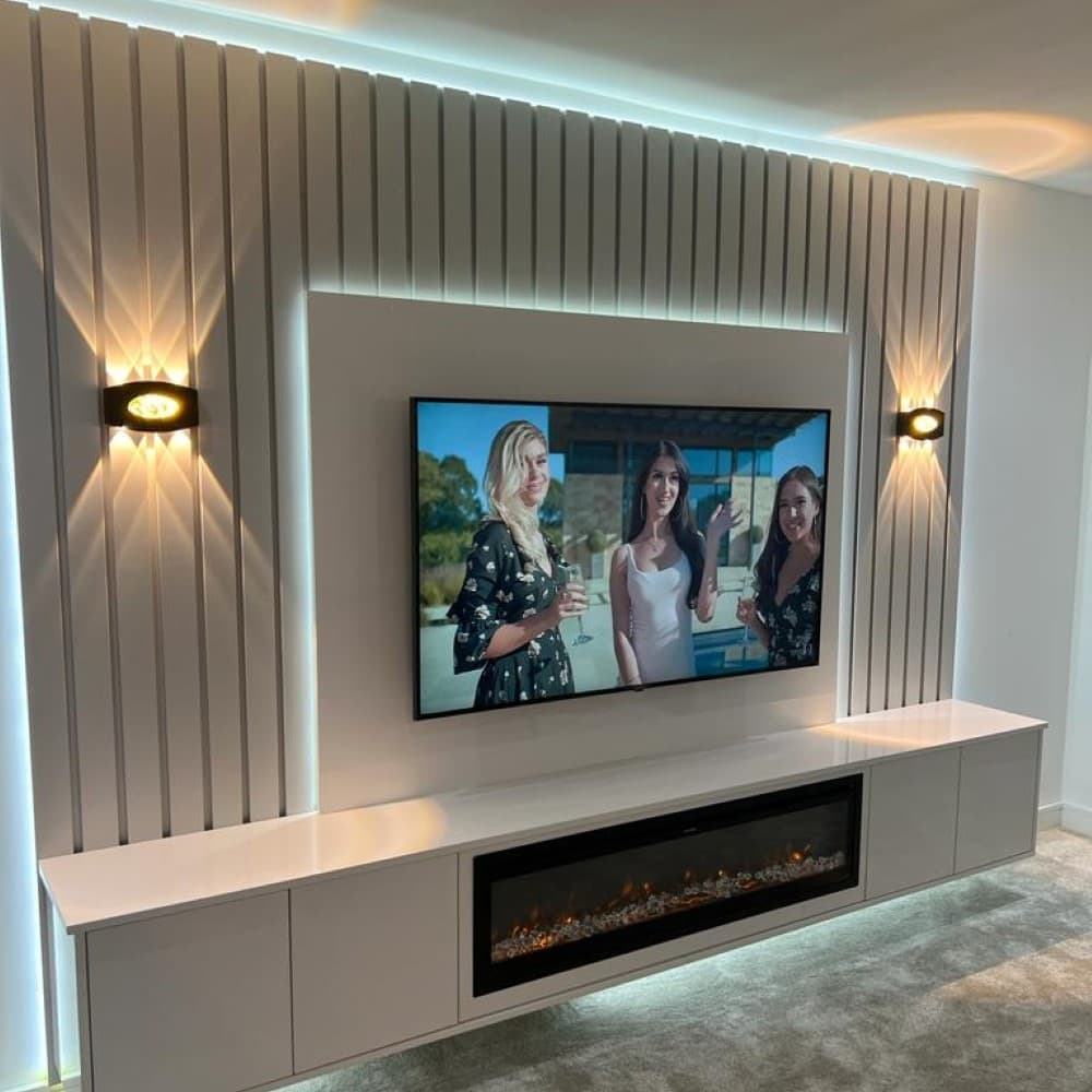 Custom media wall unit with recessed lighting and floating shelves.
