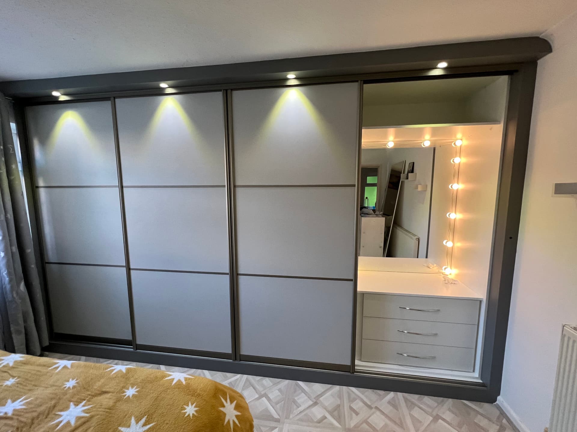 Illuminated fitted sliding wardrobe with integrated vanity section in a Didsbury loft