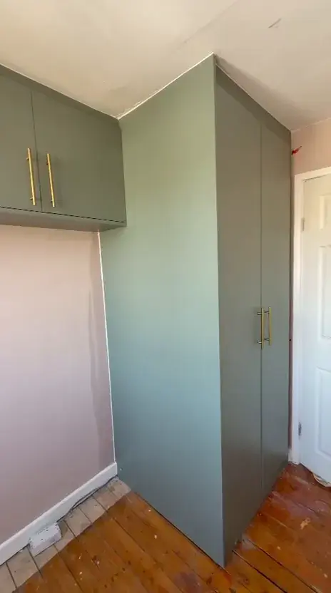 After: sage green fitted wardrobe and overhead cabinet with brass handles built around a bedroom boiler
