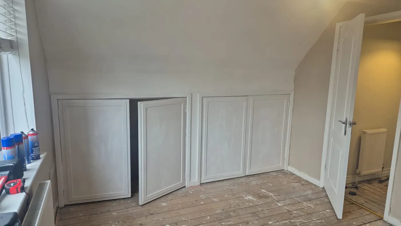 Before: small low cupboards with plain doors under a sloping bedroom ceiling
