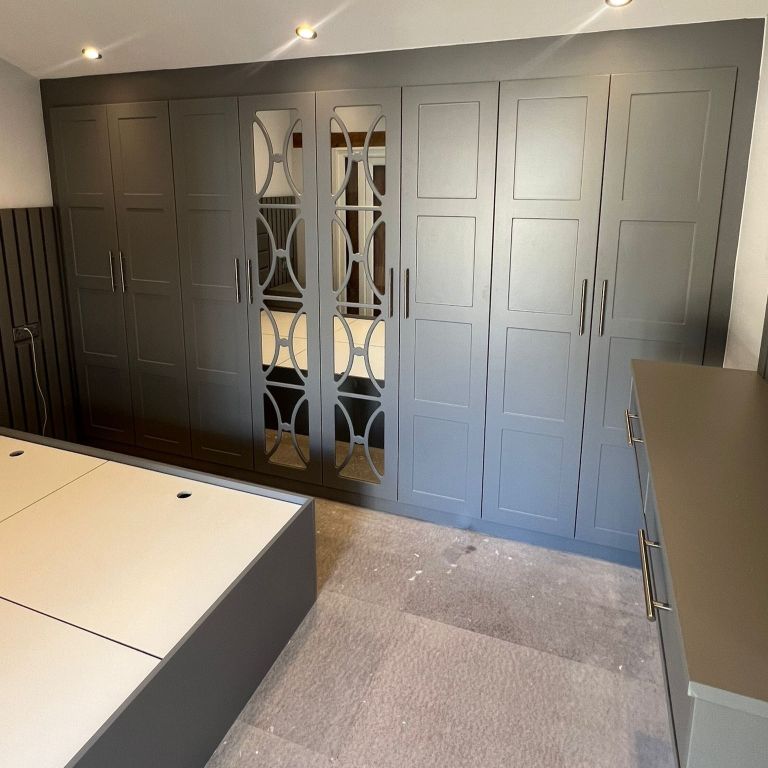 A shaker‑style fitted wardrobe with mirrored panels, offering a blend of traditional craftsmanship and modern functionality.