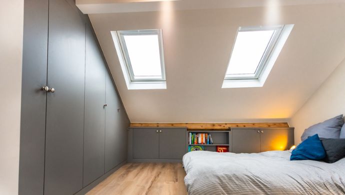 Bright, low sloped ceiling bedroom with light colors and space-saving furniture