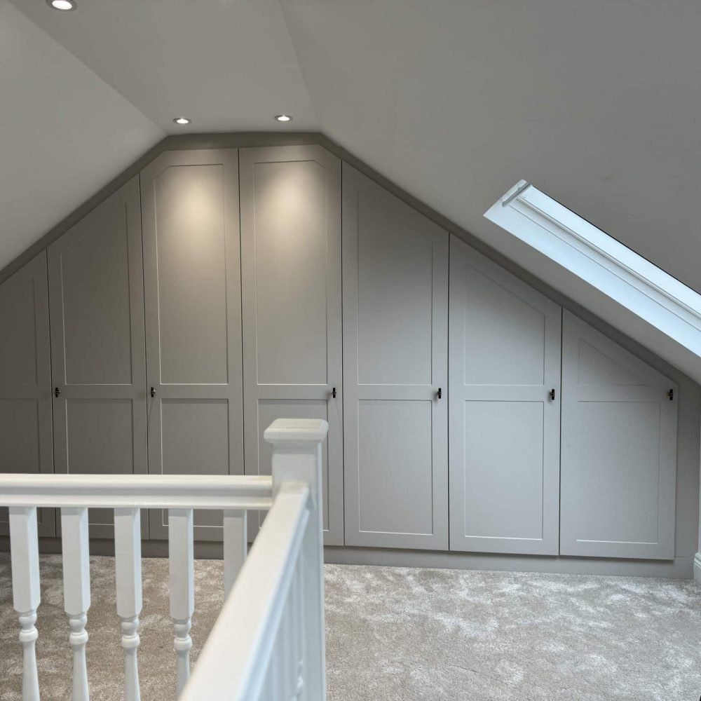 White shaker-style fitted wardrobe furniture built for attic with sloped ceiling