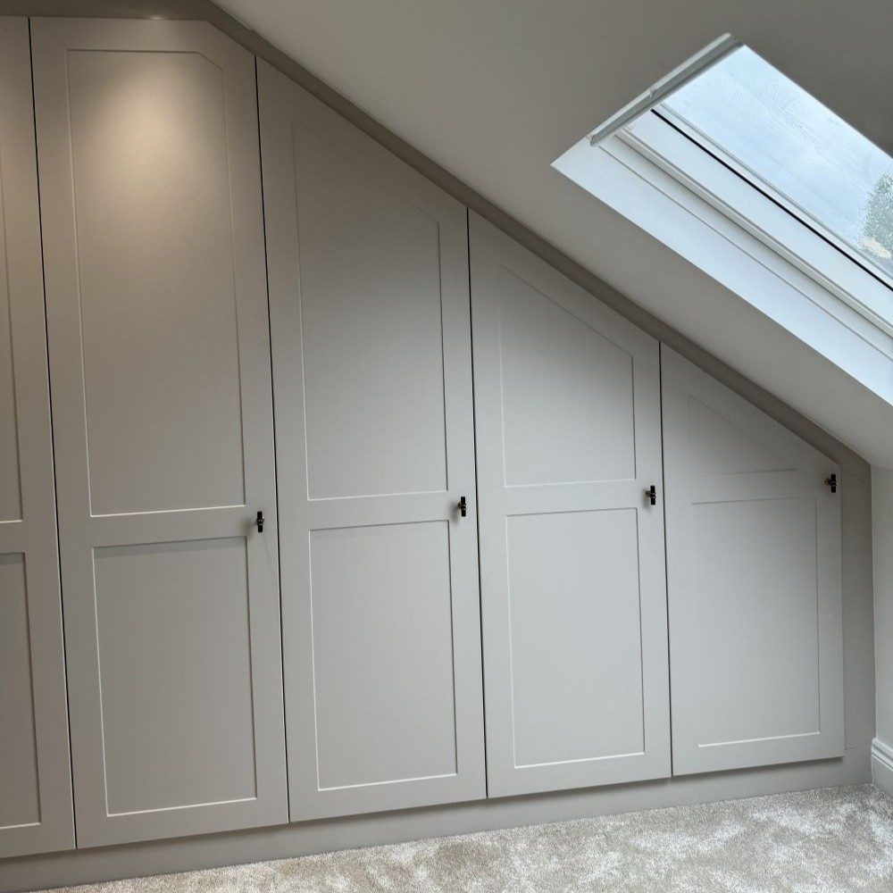 Fitted wardrobe installed under sloped loft ceiling to maximize tricky storage areas.