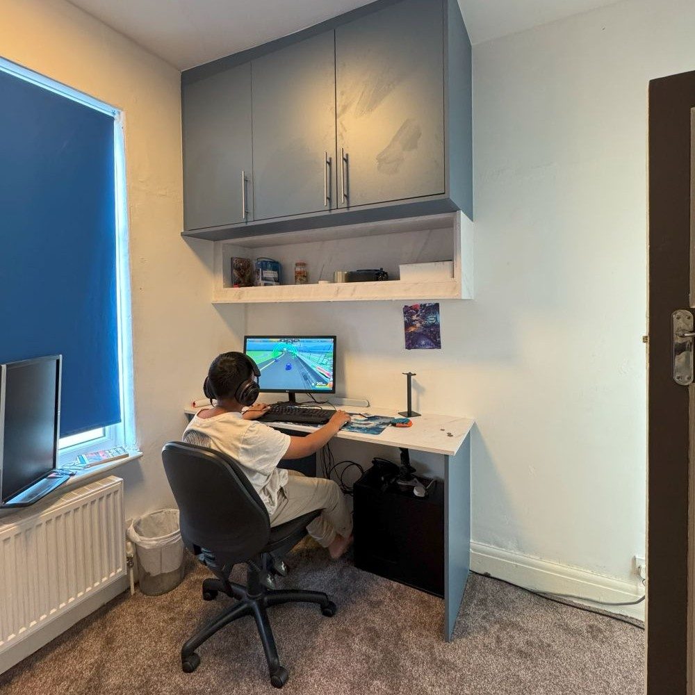 Custom fitted desk and cabinetry for home office workspace with overhead storage.
