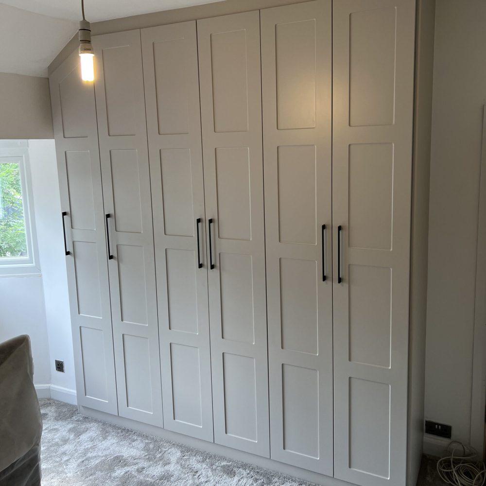 Shaker-style fitted wardrobe furniture with classic panelled doors and matte finish in a traditional bedroom
