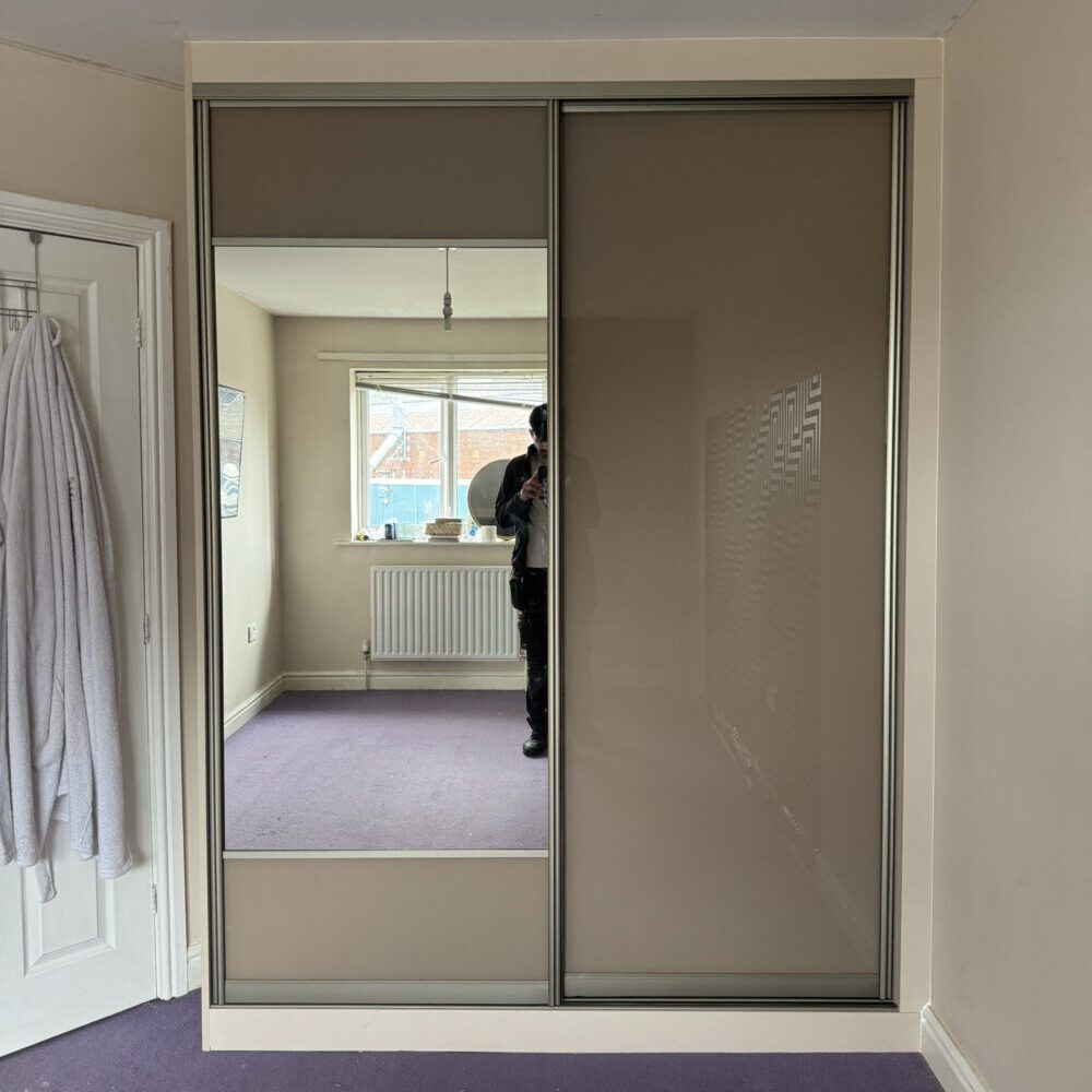 Custom sliding door fitted wardrobe furniture in a modern bedroom with soft lighting